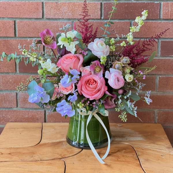 Pink and white floral arrangement in a glass vase with a ribbon