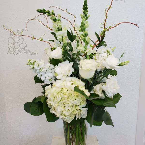 White floral arrangement in a clear glass vase with tall branching stems