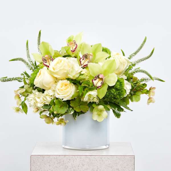 Green and white floral arrangement in a glass vase