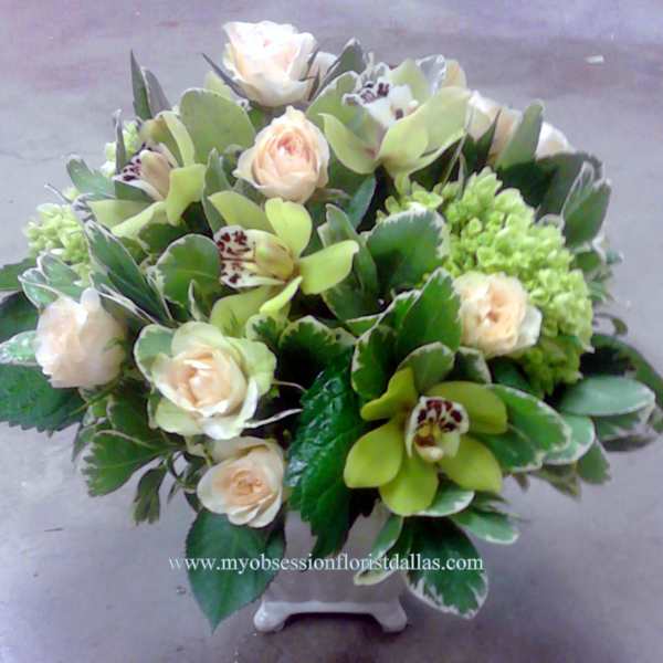Bouquet of pale roses and green orchids in a white vase