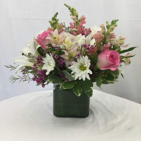 Pink and white mixed flower arrangement in a square vase