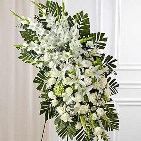 Large white funeral spray with lilies and roses on a stand