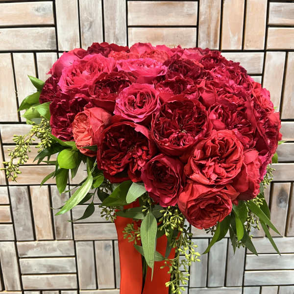 Red rose bouquet with greenery in a red vase