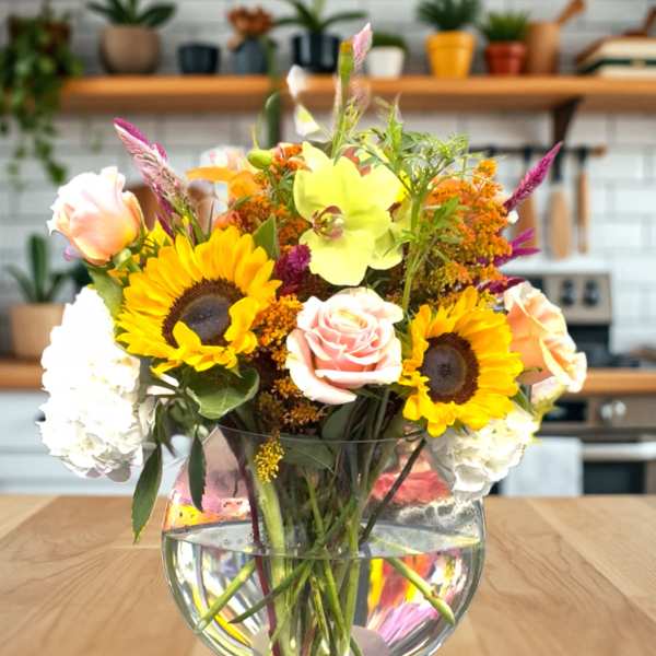 Mixed bouquet with sunflowers, roses, and hydrangeas in a glass vase
