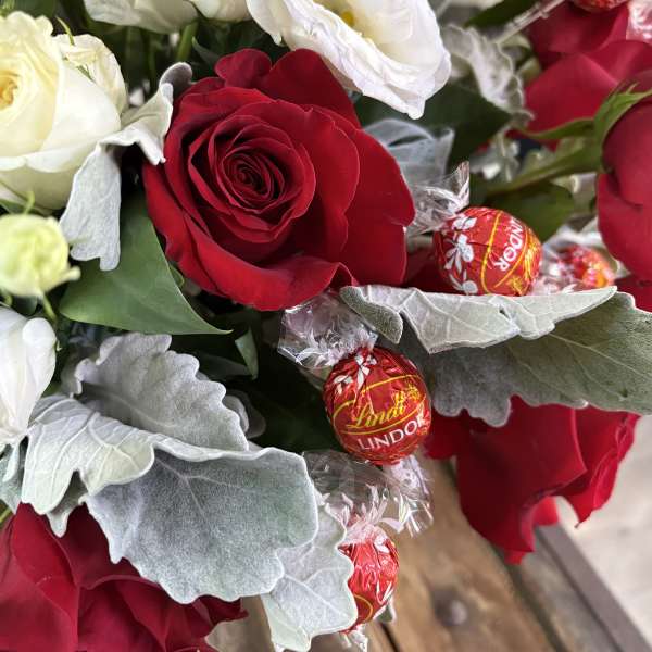Bouquet of red and white roses with wrapped chocolates