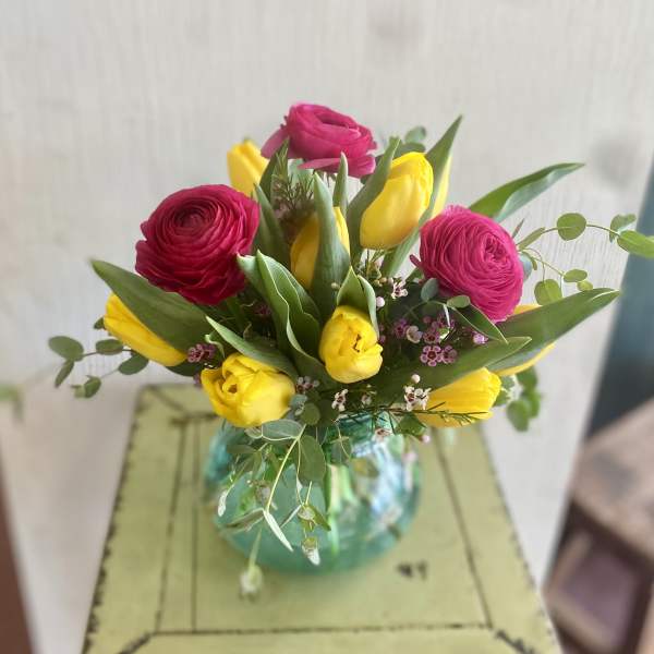 Bouquet of pink ranunculus and yellow tulips in a glass vase