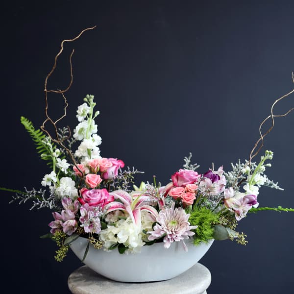 Pink and white floral arrangement in a white bowl vase