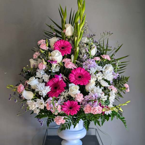 Tall mixed floral arrangement in a white vase with pink and white blooms