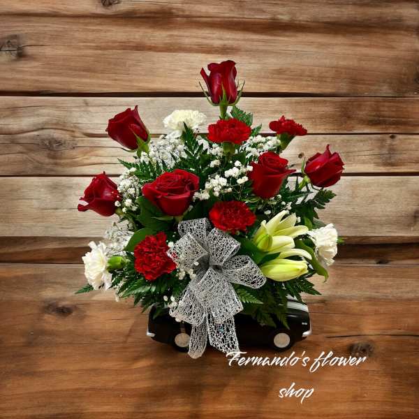 Red roses and carnations in a black car-shaped container with a silver bow