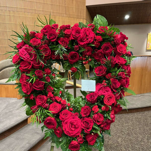 Heart-shaped wreath of red roses on a stand