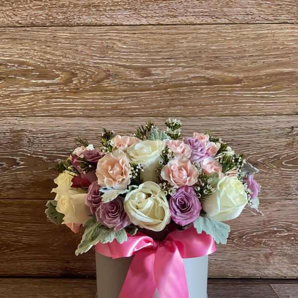 Pink and white rose arrangement in a round box with a pink ribbon