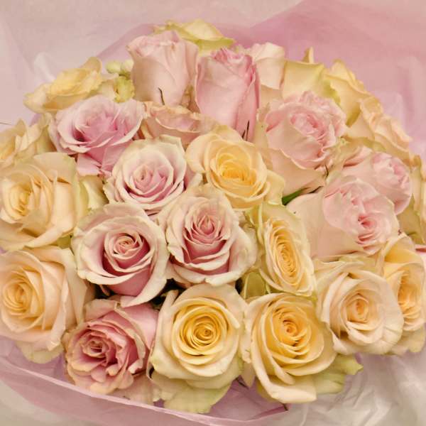 Bouquet of pale pink and cream roses wrapped in pink tissue