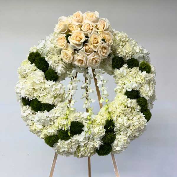 White floral wreath with cream roses on a stand