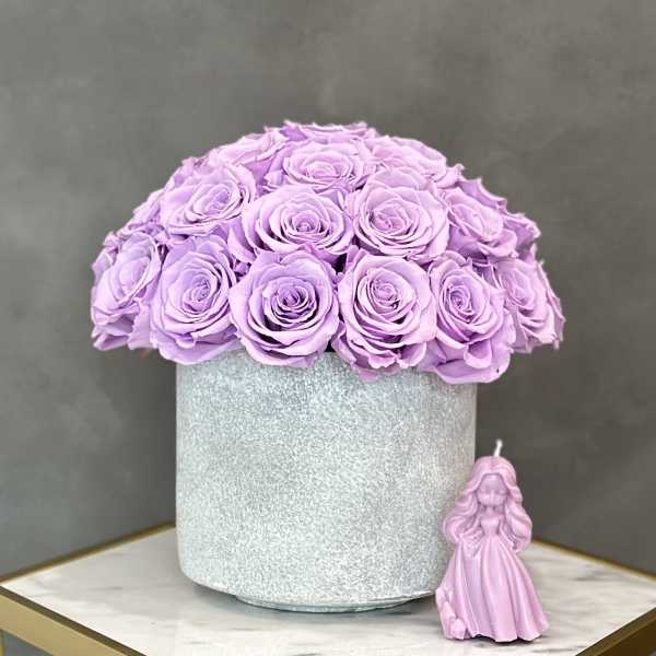 Lavender roses in a silver round box with a small pink figurine beside it