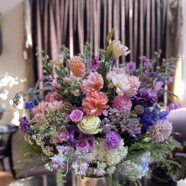 Mixed bouquet of pink, purple, and white flowers in a metallic vase