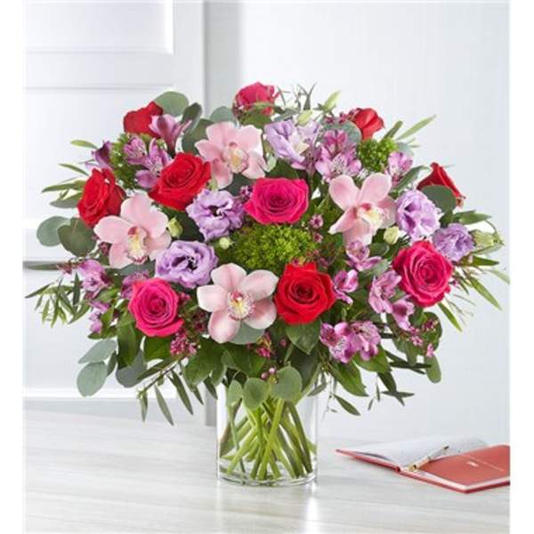 Bouquet of red and pink roses with orchids in a glass vase