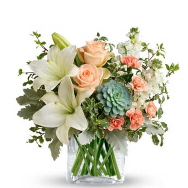 Bouquet of white lilies, peach roses, and blue-green blooms in a clear vase