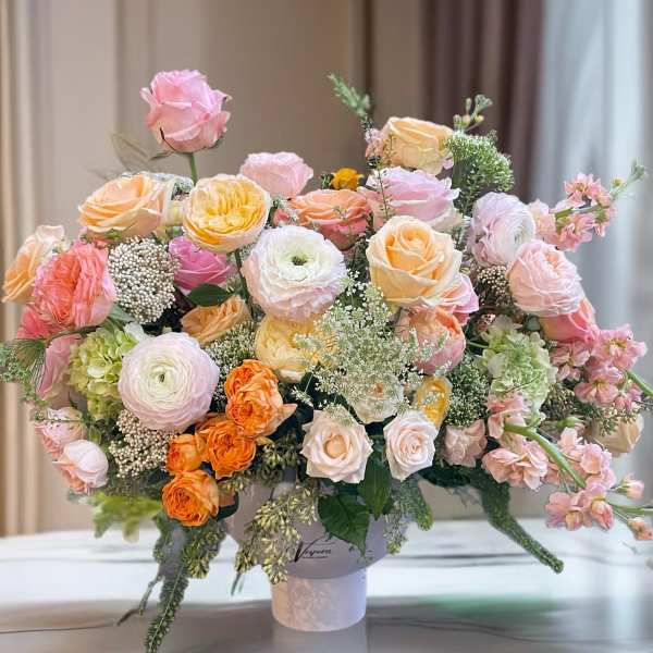 Large pastel rose arrangement in a white vase