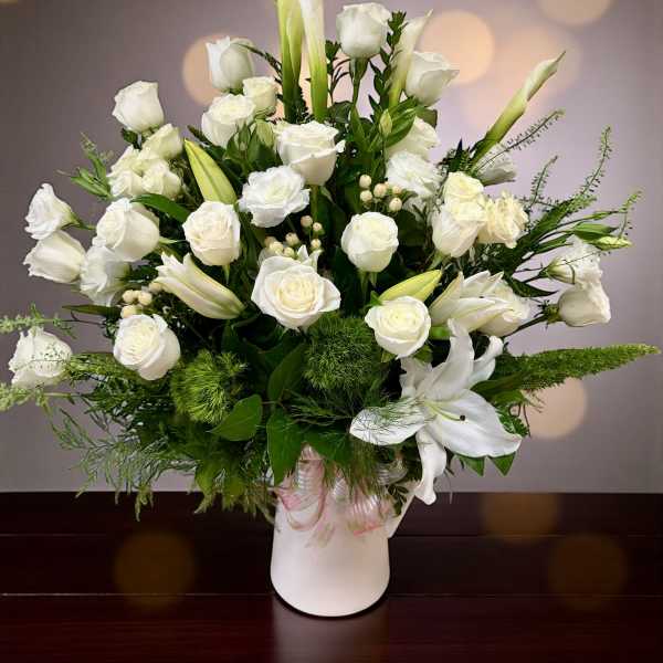 White roses and calla lilies arranged in a white vase