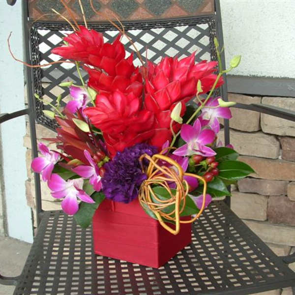 Red and pink tropical flower arrangement in a red box