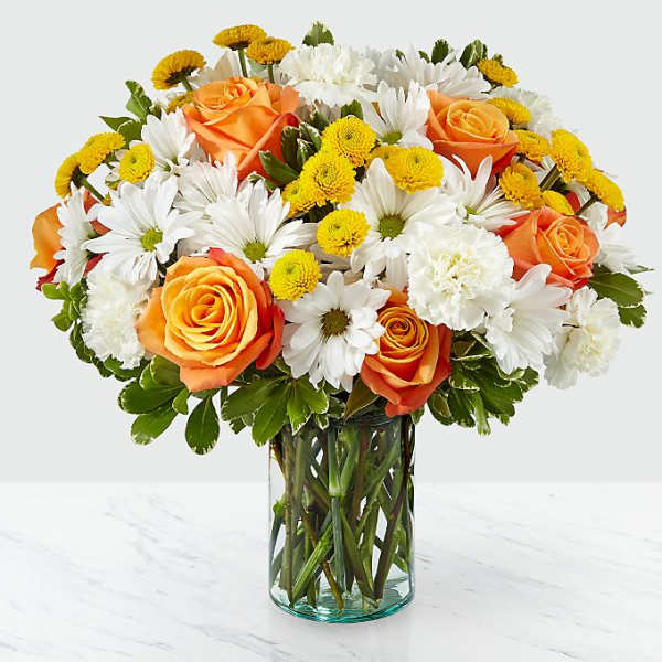 Bouquet of orange roses, white daisies, and yellow button flowers in a glass vase