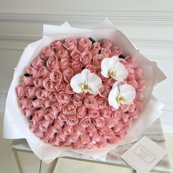 Large bouquet of pink roses with three white orchids