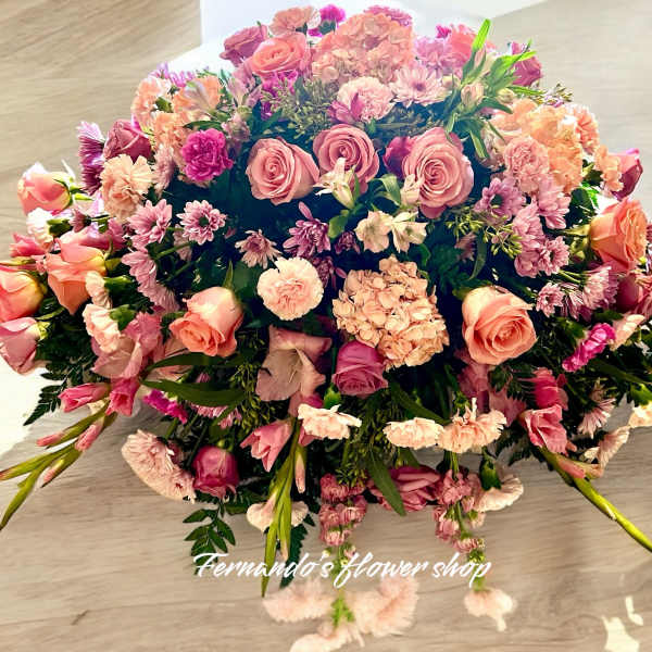 Low dome of pink and peach roses, carnations, and mums in a lush rounded centerpiece