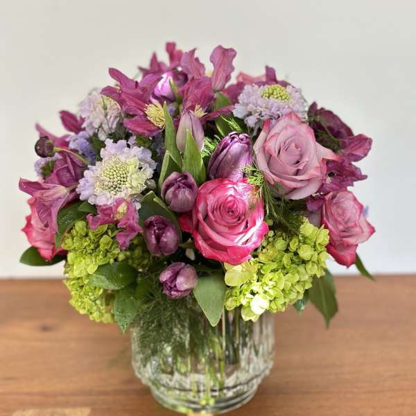 Pink and purple flower arrangement in a clear glass vase