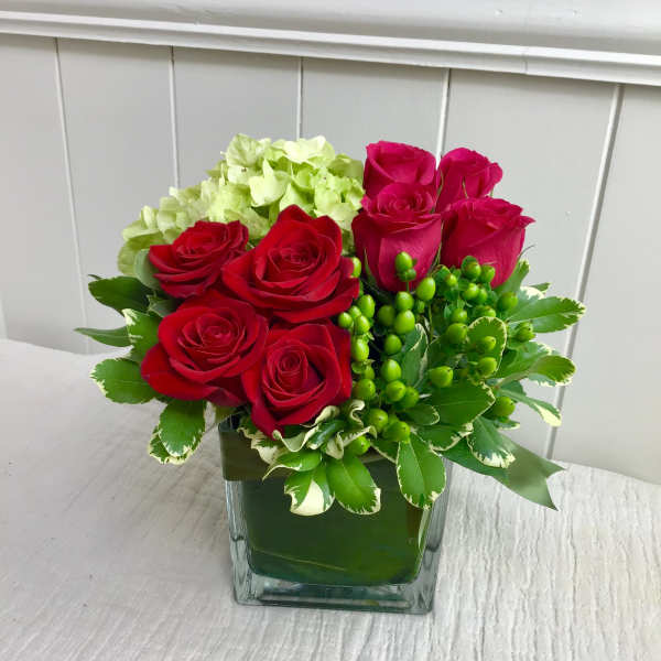 Red roses and green hydrangea in a square glass vase