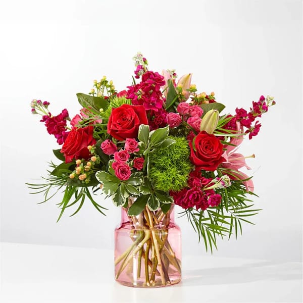 Bouquet of red and pink flowers in a pink glass vase