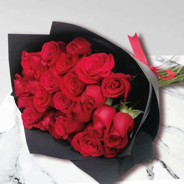 Bouquet of red roses wrapped in black paper with a pink ribbon