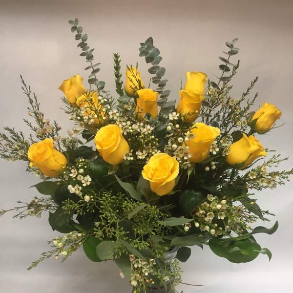 Yellow roses arranged in a clear glass vase with white filler flowers