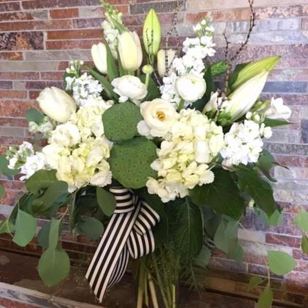 White floral arrangement with lilies, hydrangeas, and a striped ribbon