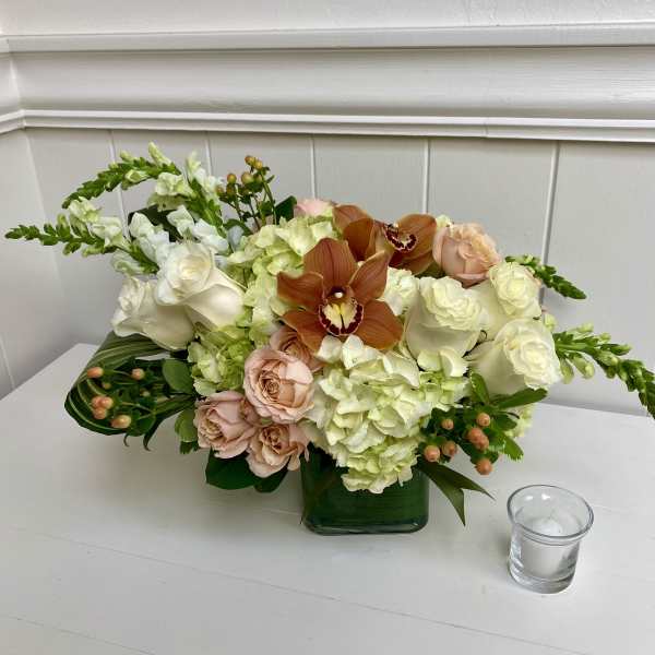 Mixed bouquet with white roses, pale hydrangeas, and orange orchids in a green vase