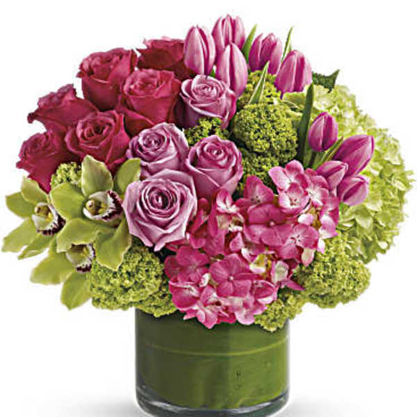 Pink roses and tulips arranged in a green glass vase
