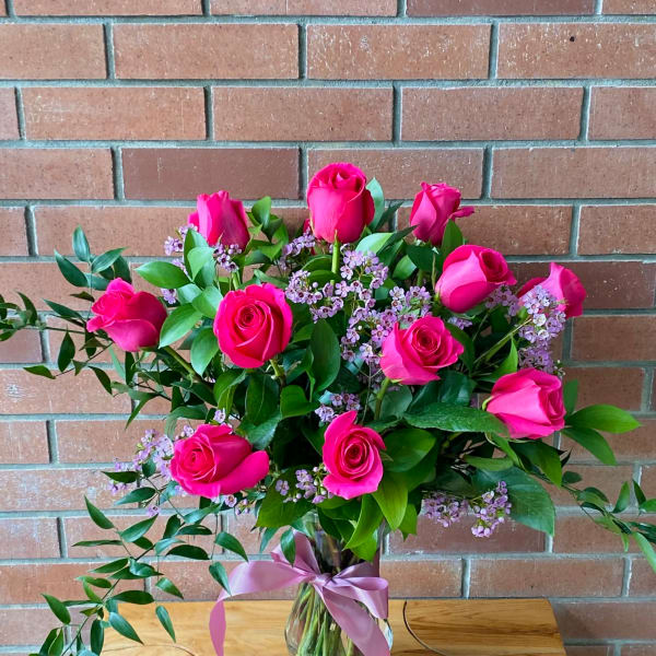 Pink roses arranged in a glass vase with a ribbon