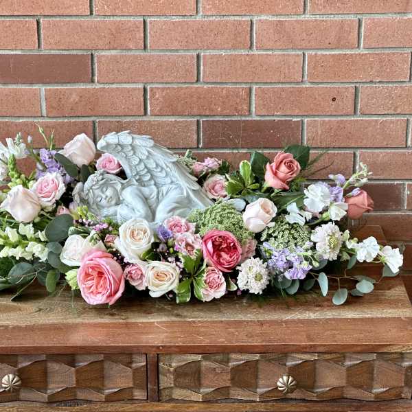 Pink and white rose arrangement with a sleeping angel statue