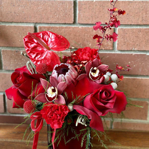 Red floral arrangement in a square glass vase
