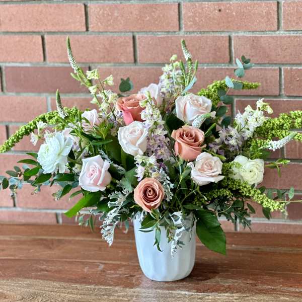 Arrangement of blush and white roses in a white vase