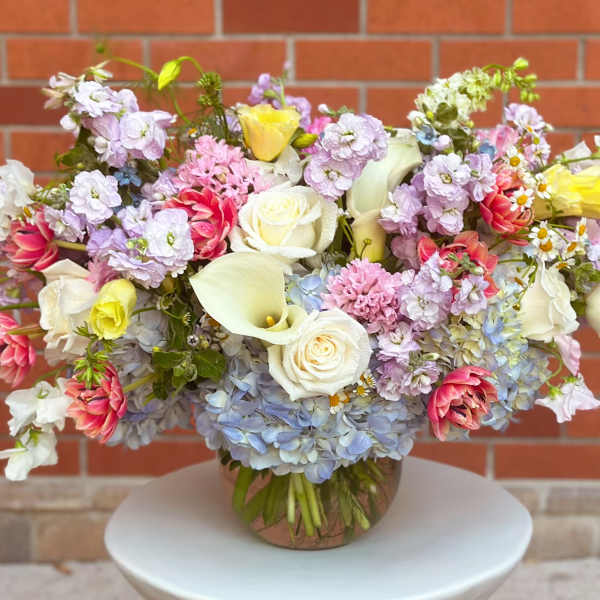 Mixed pastel bouquet in a round vase with roses, calla lilies, and hydrangeas