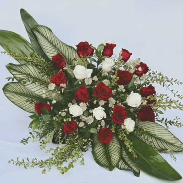 Red and white rose arrangement with large patterned leaves