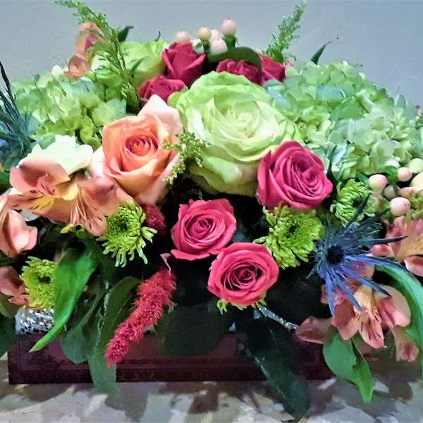 Low floral centerpiece with pink and green roses in a rectangular container