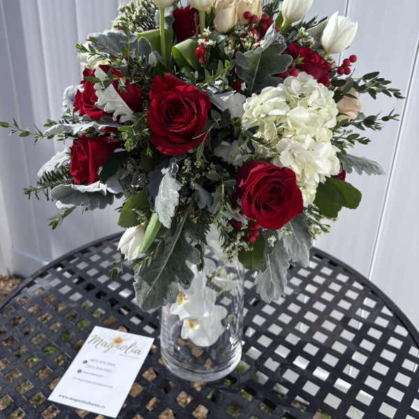 Bouquet of red roses and white tulips in a clear glass vase