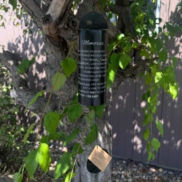 Black memorial wind chime hanging from a tree branch