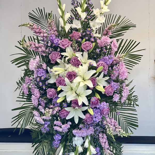 Standing floral spray with purple roses, white lilies, and lavender flowers