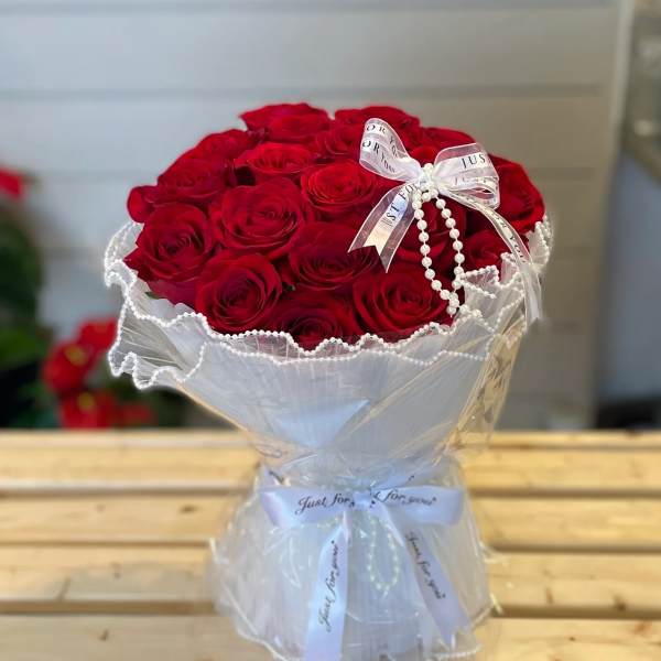 Bouquet of red roses wrapped in white paper with a ribbon