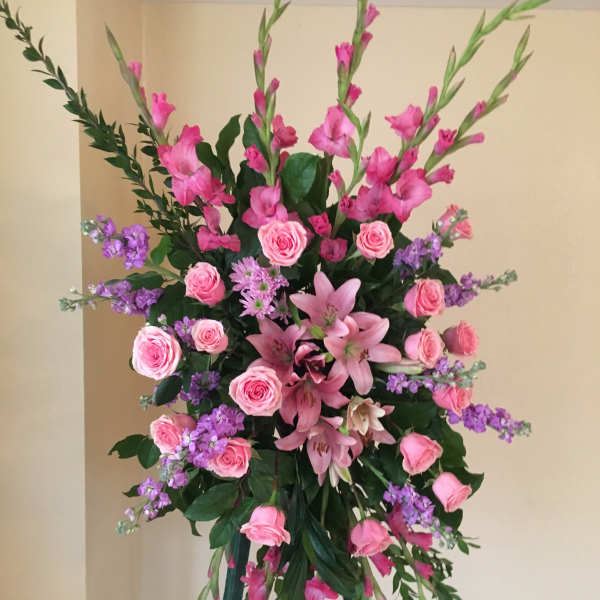 Standing floral spray with pink roses, lilies, and purple accents