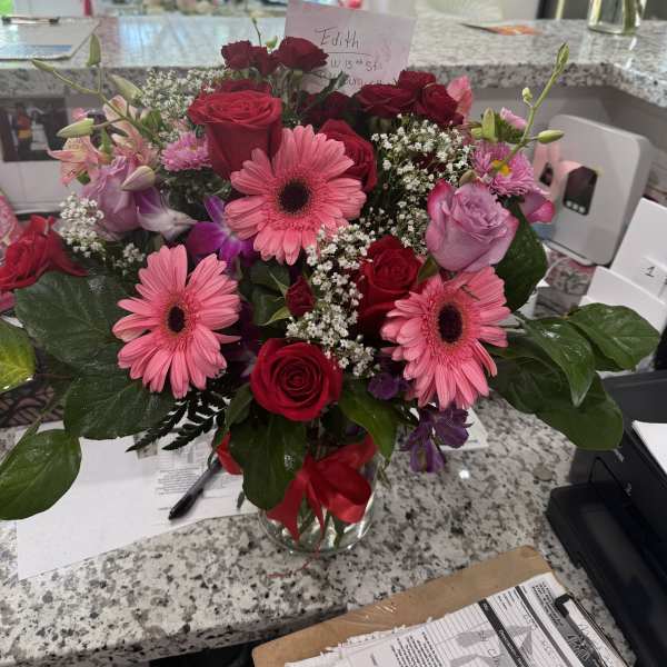 Mixed bouquet of pink gerbera daisies and red roses in a glass vase