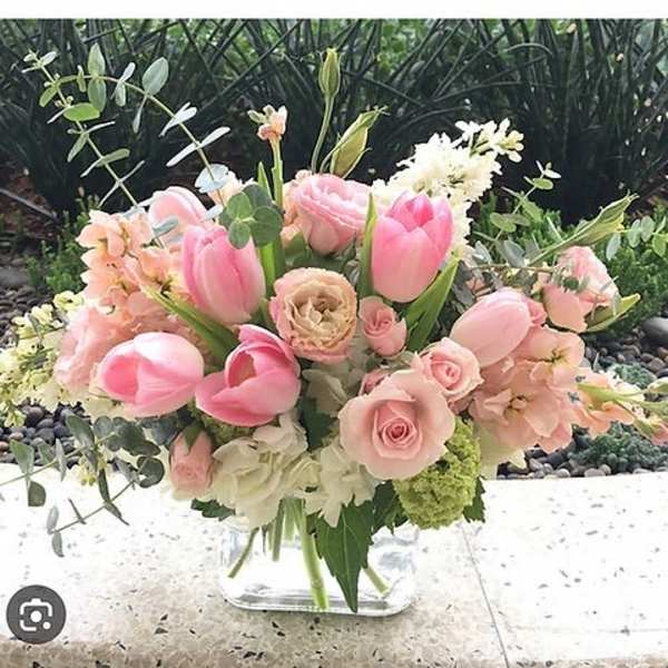 Pink tulips and roses arranged in a clear glass vase