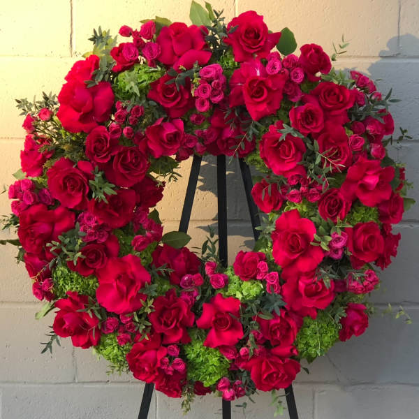 Heart-shaped wreath of red roses and pink spray roses on an easel